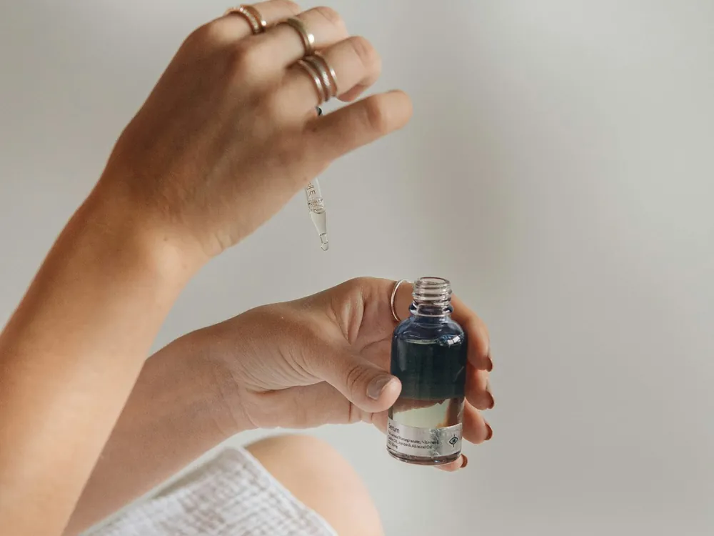 Hands holding a small serum bottle with a glass dropper