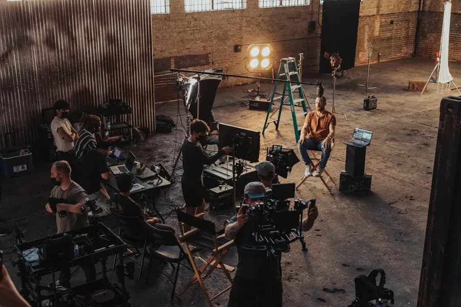 Film crew gathered around a camera rig on a lit set